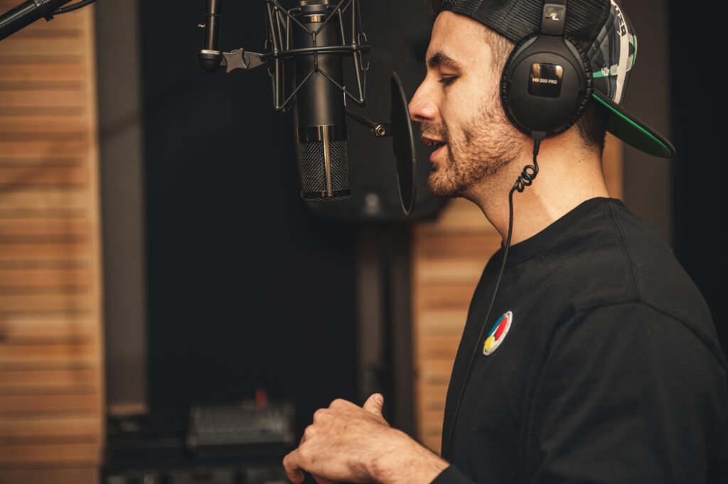 pexels-photo-3990842-3990842 A man wearing headphones and recording vocals in a music studio with a microphone.